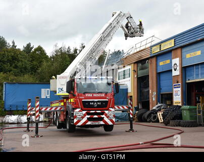 Devon, UK. 9. September 2016. Tiverton Feuer: Die Szene von einem Großbrand in den Räumlichkeiten des Warren Hughes Möbelhersteller in Ormidale Square, Tiverton Business Park, Devon, am 16.00 BST auf Freitag, 9. September 2016. Die Feuerwehr wurden bei 11,23 genannt. Fünf Stunden waren später mindestens 6 Feuerlöschfahrzeuge noch am Tatort, darunter zwei Hebebühnen. Personal in den benachbarten Einheiten wurden auch unter anderem die Räumlichkeiten der North Devon Reifen und nationalen Reifen & Autocare evakuiert. Bildnachweis: Tim Squires/Alamy Live-Nachrichten Stockfoto