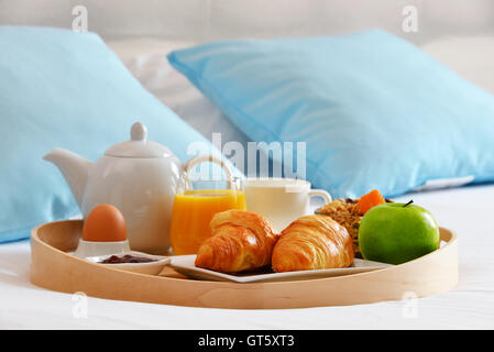 Frühstück auf Tablett im Bett im Hotelzimmer. Stockfoto