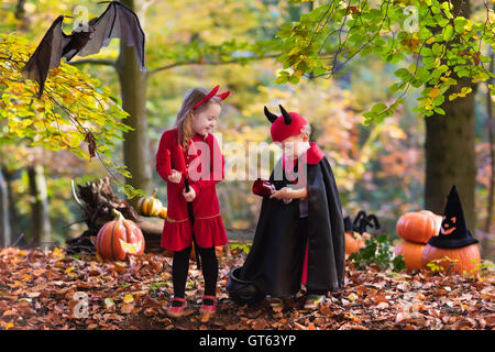 Zwei lustige Kinder tragen Teufel und Vampir Kostüm mit roten Hörnern und Trident Süßes oder Saures an Halloween. Stockfoto