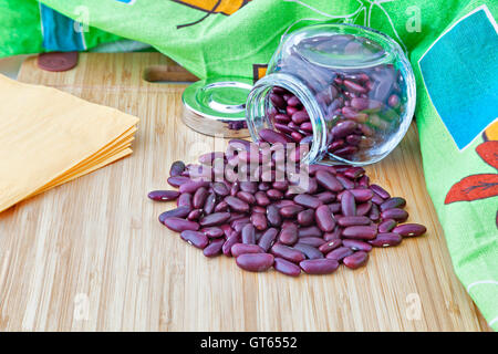 Dunkle rote Kidney-Bohnen in ein Glas mit Servietten auf einem Holzbrett Stockfoto