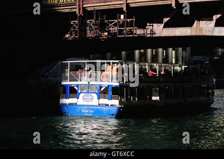 Eine Chicago Water Taxi/tour Boot Fänge ein Splitter des späten Tages Licht, während Sie unter einer Brücke auf den Chicago River. Chicago, Illinois, USA. Stockfoto