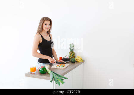 langhaarige junge Frau bereitet eine moderne und stilvolle Küche gesunde Gemüsesalat Stockfoto
