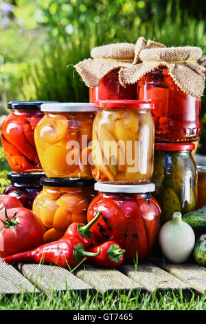 Gläser mit eingelegtem Gemüse und Obst im Garten. Marinierte Lebensmittel. Stockfoto
