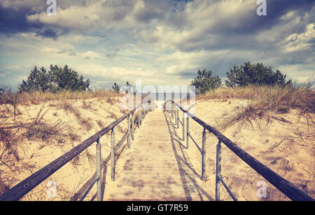 Vintage getönten Holz Wanderweg führt zu einem Strand an einem regnerischen Tag. Stockfoto