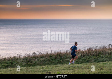 Ein Mann läuft entlang der South West Coastal Path zwischen Newquay und Watergate Bay in Cornwall. Stockfoto