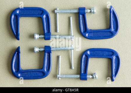 Vier blaue g-Stahlschellen übersichtlich auf einem grauen Hintergrund Co DIY, Renovierung, Reparatur und Bau von oben gesehen. Stockfoto