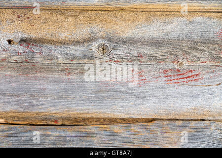 Alten trockenen verwitterte Holz Hintergrundtextur mit gerissenen Bretter mit Holzmaserung und ein paar spärliche Reste von roter Farbe, full-frame Stockfoto