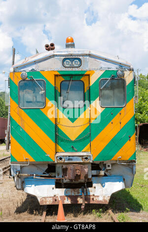 Vorderansicht eines alten Zuges oder Eisenbahn Rollmaterial geparkt auf einem Abstellgleis mit bunten grüne und gelbe Warnung Chevron, Notfall Stockfoto