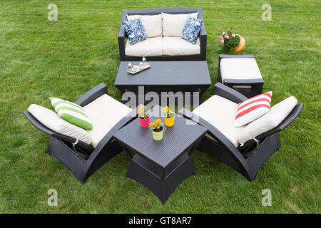 Bequeme tief moderne Gartenmöbel mit stilvollen Sesseln und einem Zweisitzer-Sofa angeordnet auf einem ordentlich gepflegten grünen Rasen Stockfoto