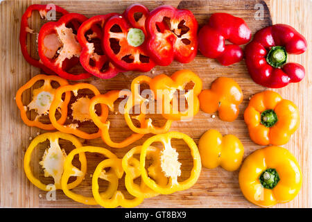 Dünne Scheiben rote und gelbe frische Paprika auf ein Holzbrett zerkleinern, Captured in High Angle View hautnah. Stockfoto
