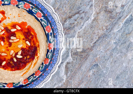 Schale mit leckeren cremigen hausgemachten Hummus gemacht mit pürierte Kichererbsen, Tahini, Öl, Zitronensaft und Knoblauch auf einem natürlichen Stein co Stockfoto