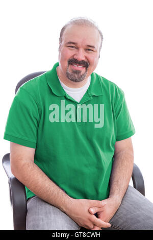 Porträt eines lächelnden bärtigen Mittelalter, tragen schlichte grüne Polo-Shirt, auf einem Stuhl sitzend mit Hände gekreuzt. Isoliert auf Stockfoto