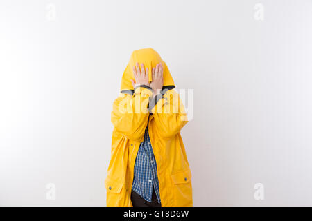 Junges Kind trägt Gelb Regenmantel versteckt Gesicht in Haube, verstecken sich vor dem Regen Konzept Bild mit Textfreiraum Stockfoto