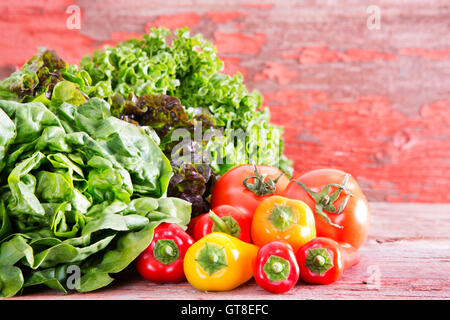 Gesunde frische Salatzutaten auf dem Bauernhof mit verschiedene Salatsorten auf rustikalen Holztafeln mit reif rot angezeigt Stockfoto