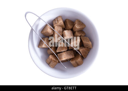 Blick von oben von Brown Sugar Cubes in einer Schüssel mit einer Zange zum servieren, isoliert auf weiss Stockfoto