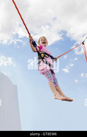 6 Jahre altes Mädchen mit Bungee-Trampolin springen, an einem sonnigen Tag, Deutschland Stockfoto