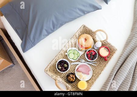 High Angle View of Wicker Frühstückstablett auf ungemachten Bett im Hotelzimmer Stockfoto