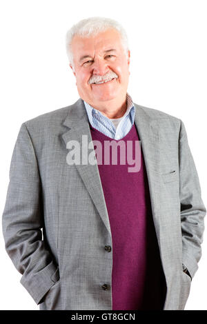 Jovial entspannt attraktive senior Mann mit weißem Haar und einen Schnurrbart stehen mit seinen Händen in den Hosentaschen lächelnd an die camer Stockfoto