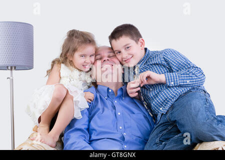 Fröhliche Vater mit zwei lachenden Kindern zusammensitzen Stockfoto