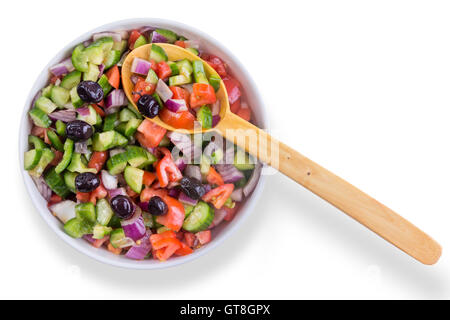 Frische bunte türkische Hirten Salat mit Oliven, serviert in einer Runde Schüssel mit einem hölzernen Löffel als gesunde Ergänzung Stockfoto