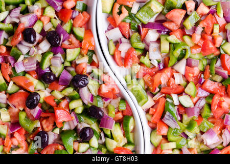 Frische bunte türkische Hirten Salat mit Tomatenwürfel, Zwiebeln und Paprika serviert mit und ohne Oliven in einer geteilten Schale Stockfoto