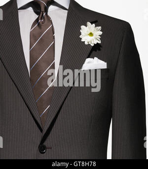 Detail einer braunen Anzug-Jacke mit Hemd und Krawatte, und weißes Taschentuch und Blume Stockfoto