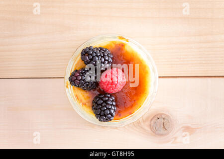 High Angle Stillleben View of Portion nachsichtig Creme Brule Pudding Dessert gekrönt mit Himbeere und Brombeere Frucht Ga Stockfoto