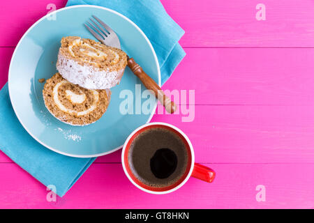 Egoperspektive zwei Stücke der Roulo Kuchen Dessert und Becher Kaffee neben Gabel auf Serviette über rosa Holztisch Stockfoto