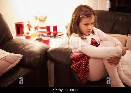 6 Jahre altes Mädchen sitzen auf einem Sofa zu Weihnachten suchen traurig, Deutschland Stockfoto