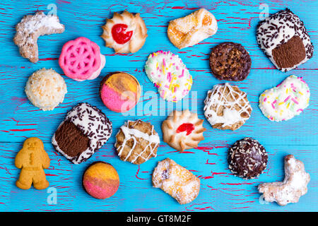 Bunte Auswahl an Luxus-Kekse oder Cookies ausgebreitet auf einem rustikalen blau Picknick-Tisch mit abblätternde Farbe in einem Overhead bac Stockfoto