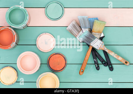 Bunte Sammlung von geöffneten Dosen verschiedene Pastelltöne von Beizen und ein Haufen von sauberen verwendeten Pinsel auf bunten gre Stockfoto