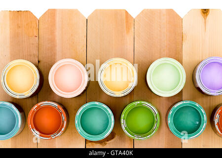 Töpfe mit bunt Beize angeordnet als untere Grenze auf einen natürlichen hölzernen Lattenzaun mit einer Auswahl an Farben, Su eröffnet Stockfoto