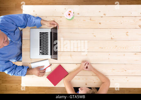 Befragung eine potenzielle Bewerber sitzen an einem hölzernen Bürotisch mit einem offenen Notebook während der Befragung ein junger Geschäftsmann Stockfoto