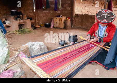 Einheimische Cusquena Frau in bunten Trachten gekleidet arbeitet auf einem Webstuhl vor ihrem Haus Stockfoto