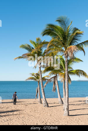 Mann mit Metalldetektor auf schönen tropischen Strand auf The Strand, Townsville, Australien mit blauem Himmel und Meer Stockfoto