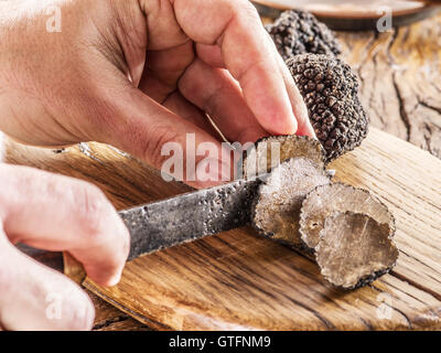 Schneiden von schwarzen Trüffeln auf dem Holzbrett. Stockfoto