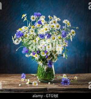 Bouquet von Kamillen und Kornblumen in der Vase auf dem Holztisch. Stockfoto