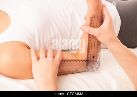 Physiotherapie-Therapeuten trainieren mit Patienten mit Gonometer, um die Beweglichkeit der Gelenke von Ellenbogen zu überprüfen Stockfoto