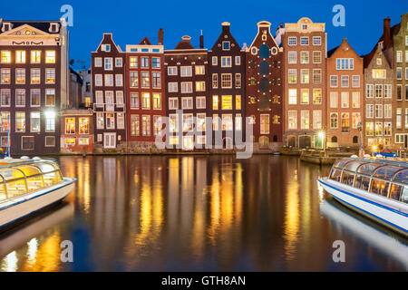 In die Nacht tanzen Häuser am Amsterdamer Kanal Damrak, Holland, Niederlande. Stockfoto