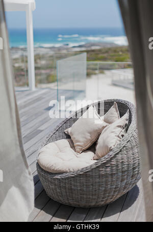 Wicker Sitz mit Kissen am sonnigen Strand Haus Terrasse mit Meerblick Stockfoto