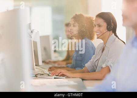 Lächelnd Geschäftsfrau mit Kopfhörer arbeiten am Computer im Büro Stockfoto