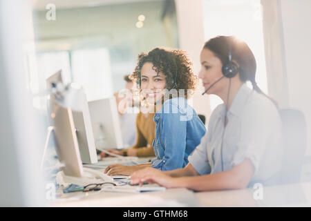 Porträt lächelnd Geschäftsfrau mit Kopfhörer arbeiten am Computer im Büro Stockfoto