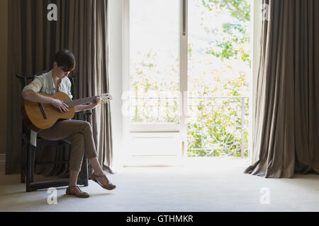 Frau spielt Gitarre am Balkonfenster Stockfoto