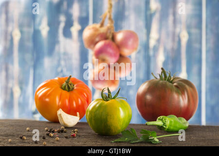 Frisches Gemüse auf alten blauen hölzernen Hintergrund - Tomaten, Petersilie, Knoblauch, Pfeffer, Zwiebel, Basilikum Stockfoto