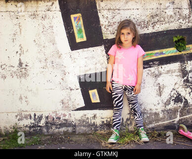 Kleines Mädchen vor Graffitiwand Stockfoto