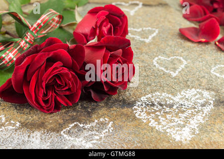 Rote Rosen mit Band auf einem Steintisch Stockfoto