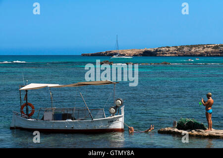 ELS Pujols Strand auf Formentera. Touristen, die aufgenommenen Bilder mit der traditionellen Fischerei Boot in Sommertag. Llaüt. Stockfoto