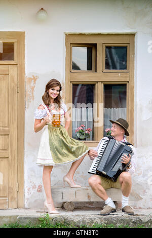 Paar in bayerischer Tracht mit Bier und Akkordeon Stockfoto