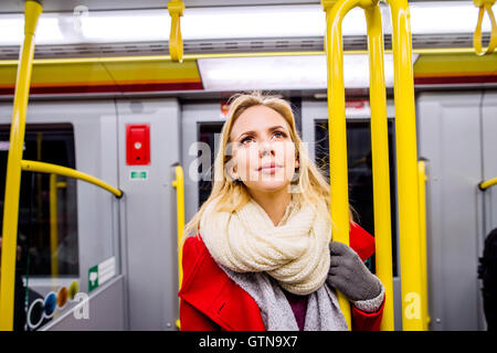 Schöne junge Frau im roten Mantel in u-Bahn Stockfoto