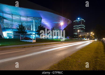 Beleuchtete Fassade der Gebäude der BMW Welt und BMW Hauptsitz mit Verkehr Trails in München in der Nacht, Bayern, Deutschland Stockfoto